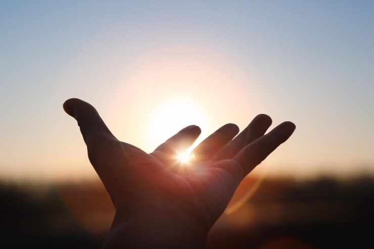 Photo strong rays of light shining between hands stretched out toward the sunrise sun