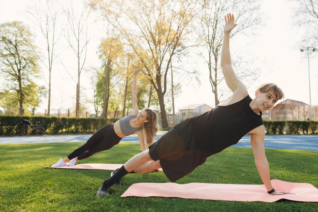 Strong sports couple man and woman make yoga exercises outdoors