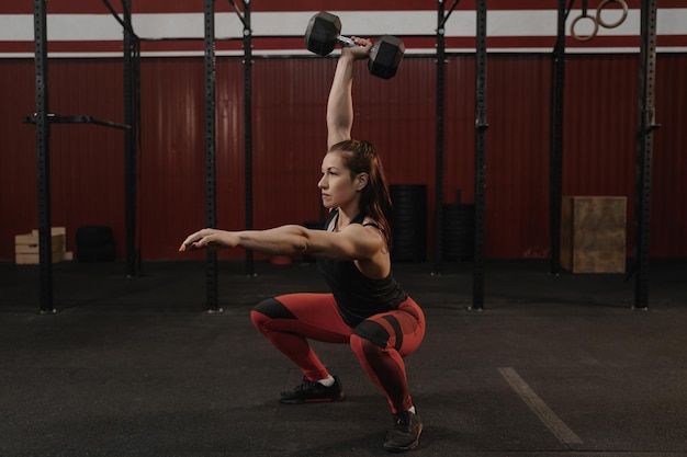 Strong sports woman doing dumbbell squats female athlete lifting weights