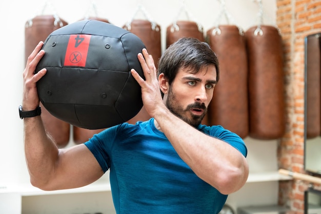 Strong sportsman doing exercise with heavy medicine ball