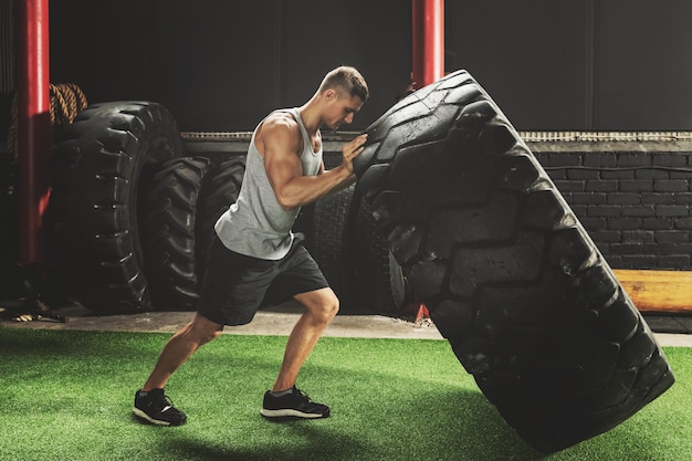 Strong sportsman doing  a tire flip exercise