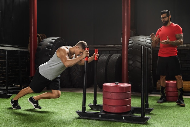 Strong sportsman during sled push exercise