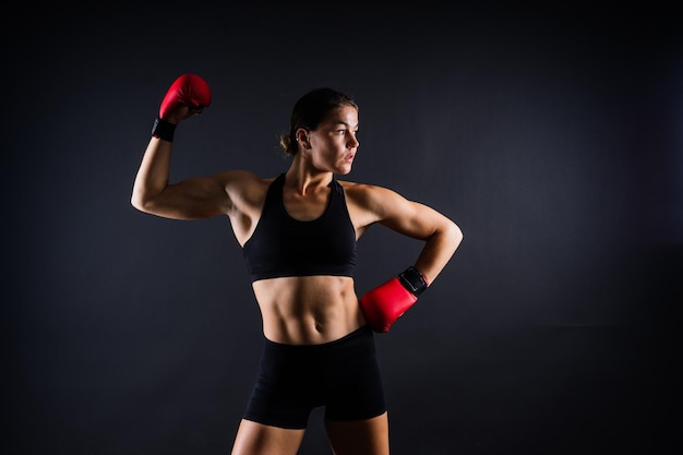 Strong sportswoman in boxing gloves prepared high kick isolated on white red yellow background