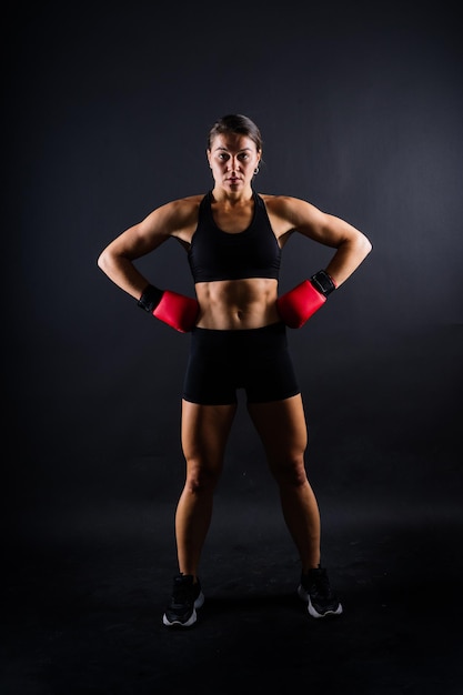 Strong sportswoman in boxing gloves prepared high kick isolated on white red yellow background