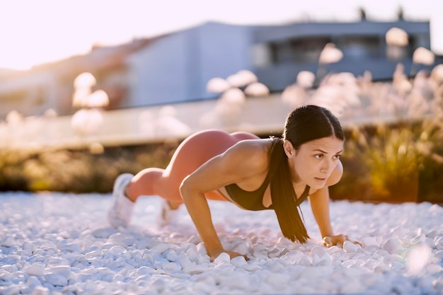 Strong sportswoman is doing push ups in urban exterior