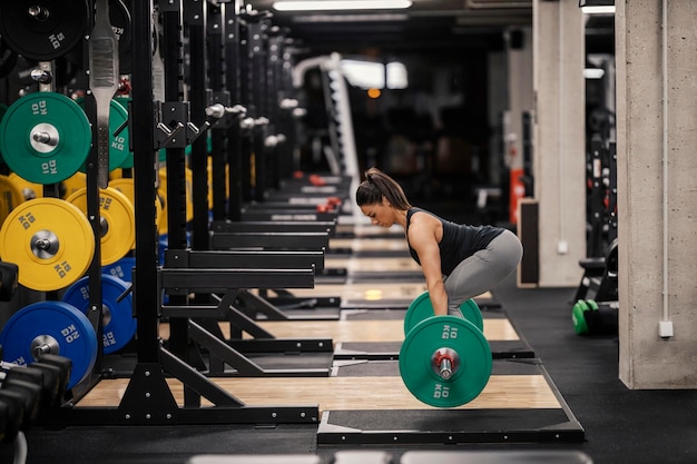 A strong sportswoman is lifting doing deadlifts in a gym