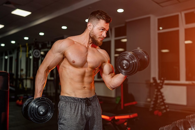 Strong sporty man doing weightlifting. Bodybuilder in contemporary dark gym.