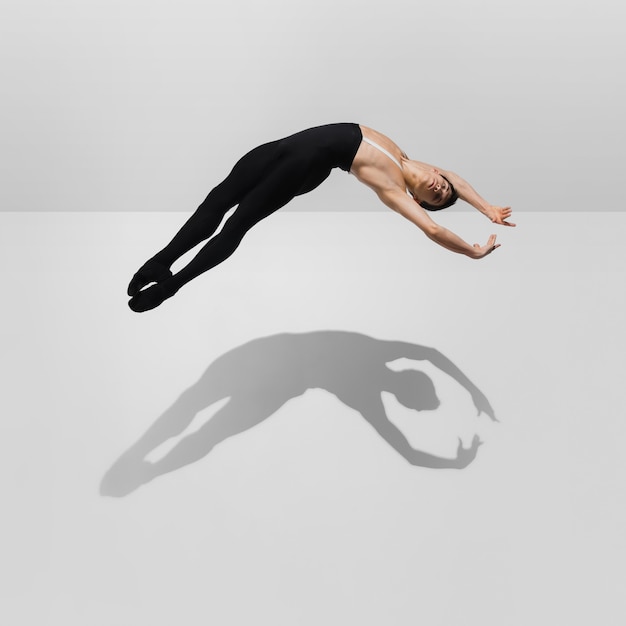 Strong Stylish young male athlete on white studio background with shadows in jump