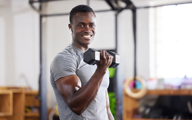 체육관에서 근육 훈련과 힘을 위해 들어올리는 흑인 남자의 강한 무게와 초상화 스마일 피트니스와 아프리카 운동선수가 운동이나 보디빌딩과 유산소 운동을 합니다.