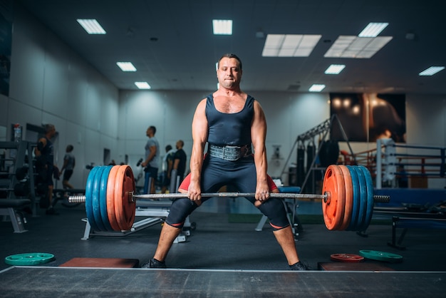 Strong weightlifter doing exercise with barbell