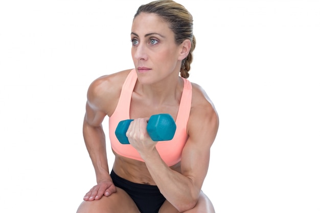 Strong woman doing bicep curl with blue dumbbell