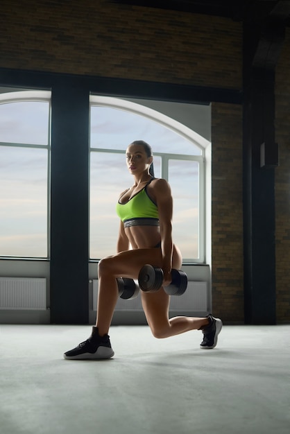 Strong woman doing fitness exercises with dumbbells.