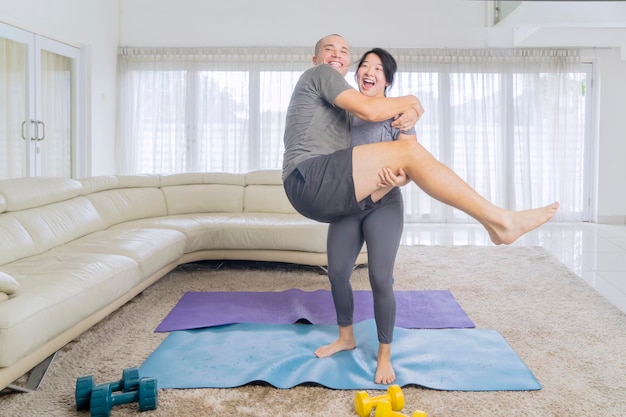 Strong woman holds husband after exercise at home