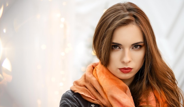 Strong woman in orange silk headscarf wrapped around her head looks strict