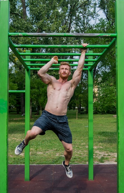 Сильный молодой человек упражнения в парке