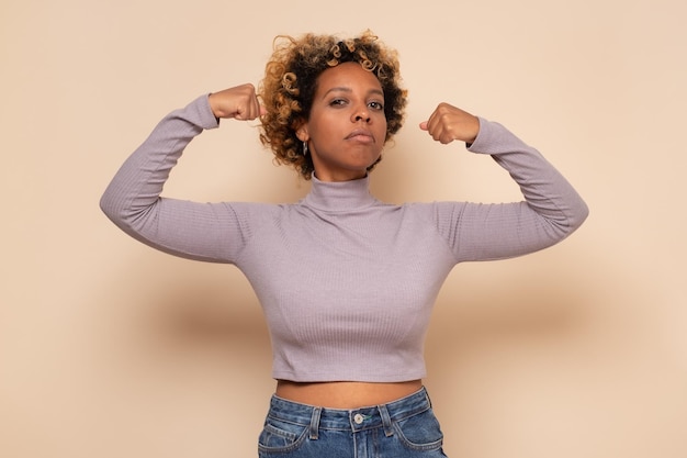 Photo strong young african woman in showing biceps being strong