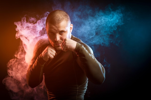 Photo a strong young dark-haired male athlete in a green sports jacket is boxing against a background