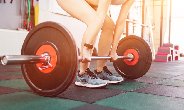 Strong young fit woman doing deadlift with a barbell in the gym. Free weight training