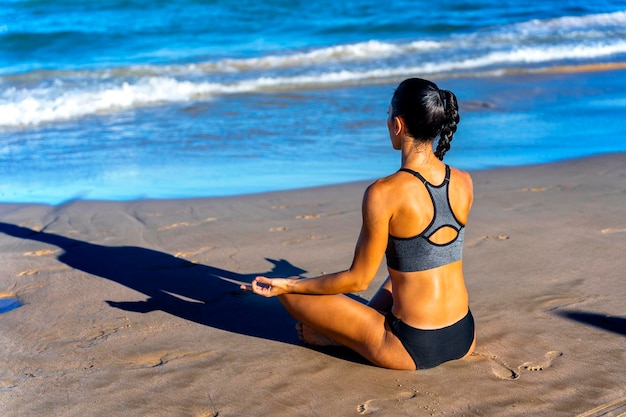 Strong young fitness woman meditate at the beach