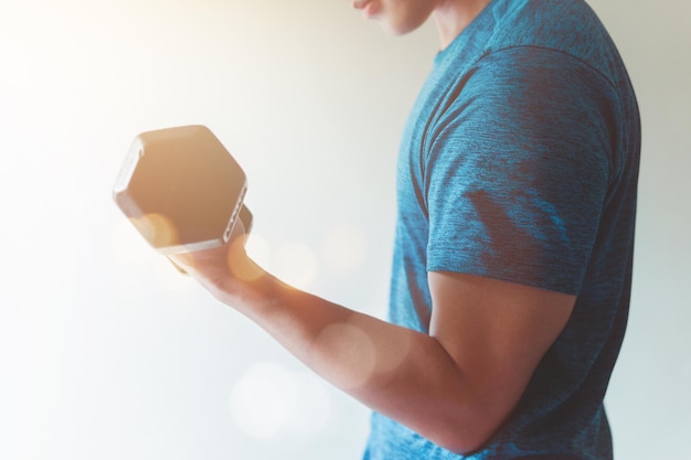 Strong young man working out with dumbbell in room on a gray background health care concept