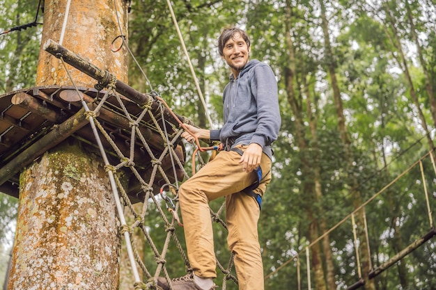 Strong young men in a rope park on the wood background