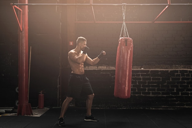 Strong young mma fighter and red punching bag