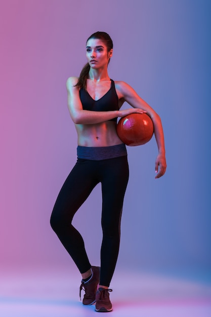 Сильная молодая спортивная женщина, стоящая с мячом