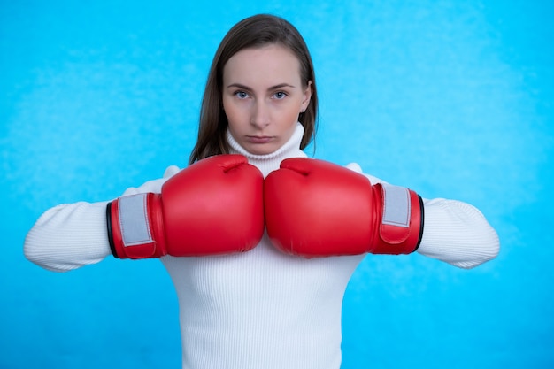 Forte giovane donna boxer in posa isolato su muro blu muro indossando guantoni da boxe.