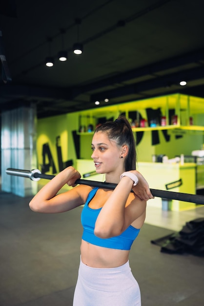 Strong young woman doing situps with a barbell