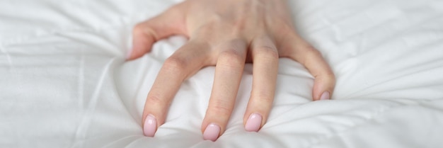 Photo strongly clenched female hand on sheet on bed