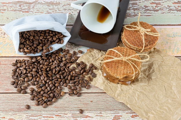 Stroopwafels stacked on brown paper, next to a lying coffee cup (top view).