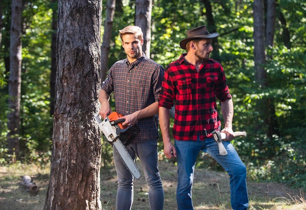 Stropers in bos. ontbossing. boswachter of stroper. man boswachter gebruik zaag en bijl. zoek brandhout voor picknickkampvuur. Overleven in de wilde natuur. mens en natuur. mannen wandelen in het bos.