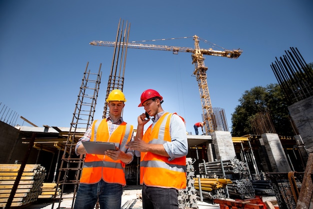 Ingegnere strutturista e architetto vestito con giubbotti da lavoro arancioni