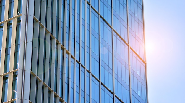 Структурная стеклянная стена, отражающая голубое небо Фрагмент абстрактной современной архитектуры