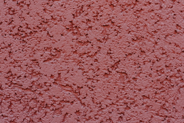 Structure of textured plaster on red wall background