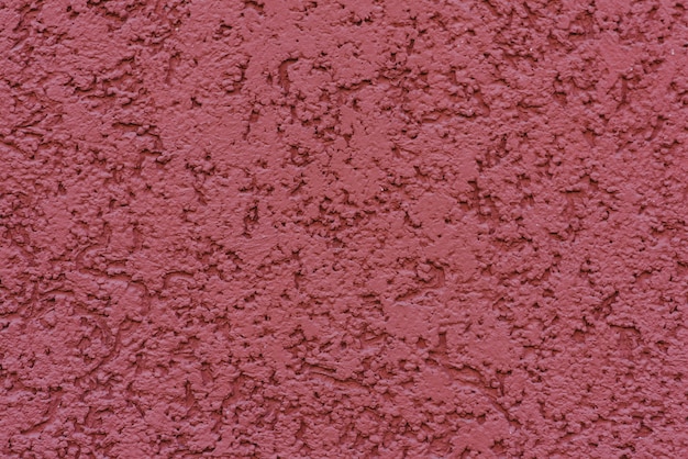 Structure of textured plaster on red wall