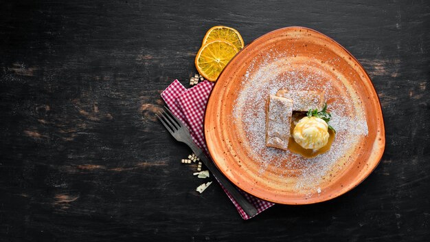 Strudel with apples and ice cream on a plate Dessert On a wooden background Free copy space Top view