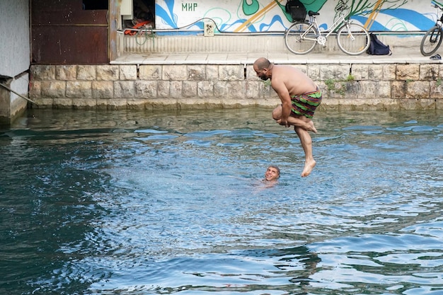 STRUGA MACEDONIA AUGUST 13 2023 Men jump from the bridge into the water of a Drim river downtown in Struga Macedonia