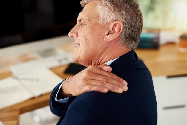 Photo struggling with unbearable shoulder pain cropped shot of a mature businessman experiencing shoulder pain while working in an office