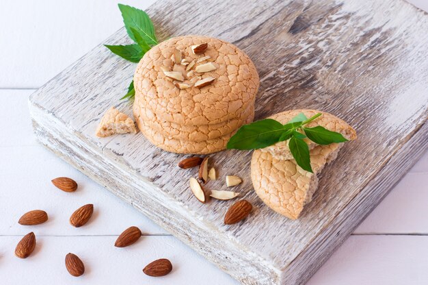 Stuck of almond cookies with mint and nuts on white cutting board.