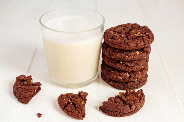 Stuck of chocolate brownie cookies and glass of coconut milk on wooden table. Homemade pastry