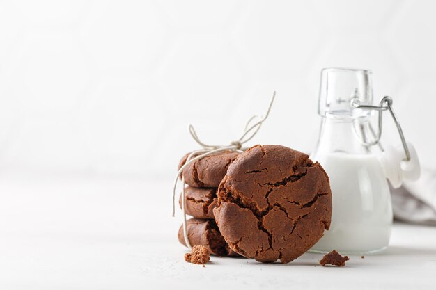 Stuck of chocolate brownie cookies on white background and milk in glass bottle Homemade