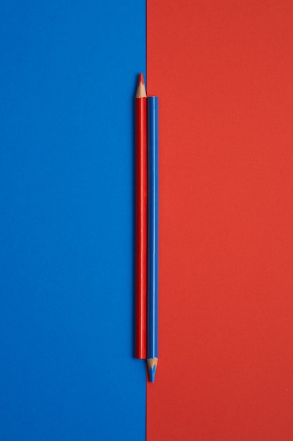 Stuck red and blue colored pencils isolated on blue and red table