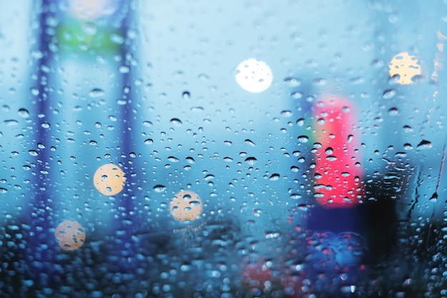 雨の日に渋滞に詰まり、フロントガラスの液滴がぼやけてボケの背景に