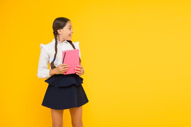 Studeer taal Thuis studeren Schattig kind studeren met leerboek Terug naar school concept Meisje houdt boek vast Schoolmeisje op gele achtergrond Oefen en verbeter leesvaardigheid voor schoolstudies