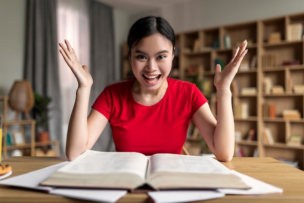 Studeer thuis vanwege covid19 Tevreden opgewonden jonge Aziatische studente met boek dat schreeuwt en zich verheugt