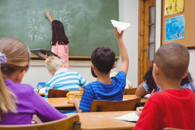 紙飛行機を投げようとしている学生