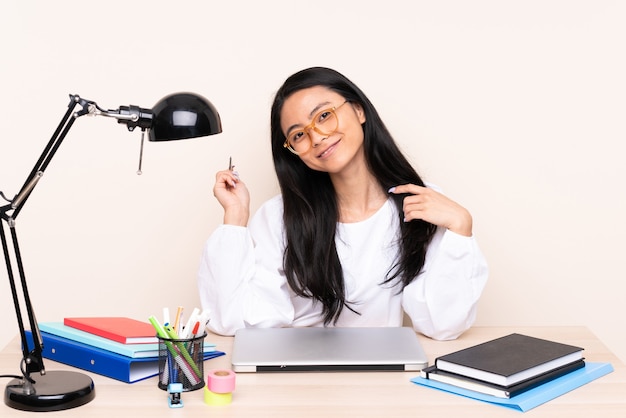 Student Aziatisch meisje op een werkplek met een laptop geïsoleerd op beige