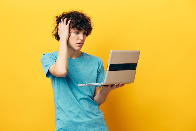 Student in blue tshirts with laptop internet yellow background