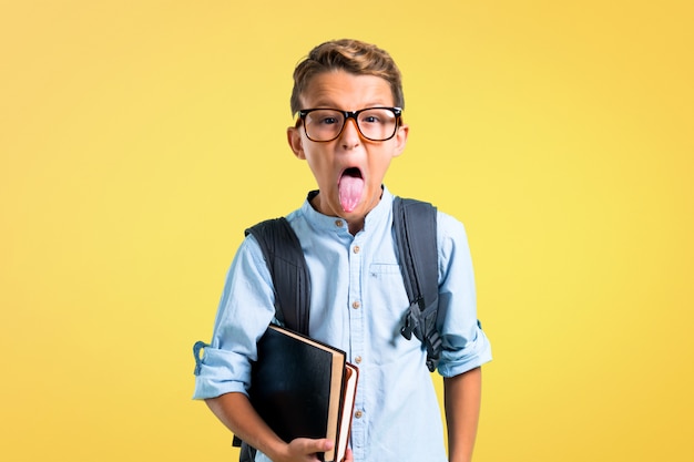 Student boy with backpack and glasses showing tongue at the camera. back to school